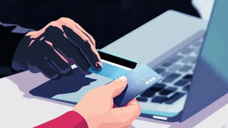 Close up hand holding credit card shadowy hand stealing through laptop online fraud uk